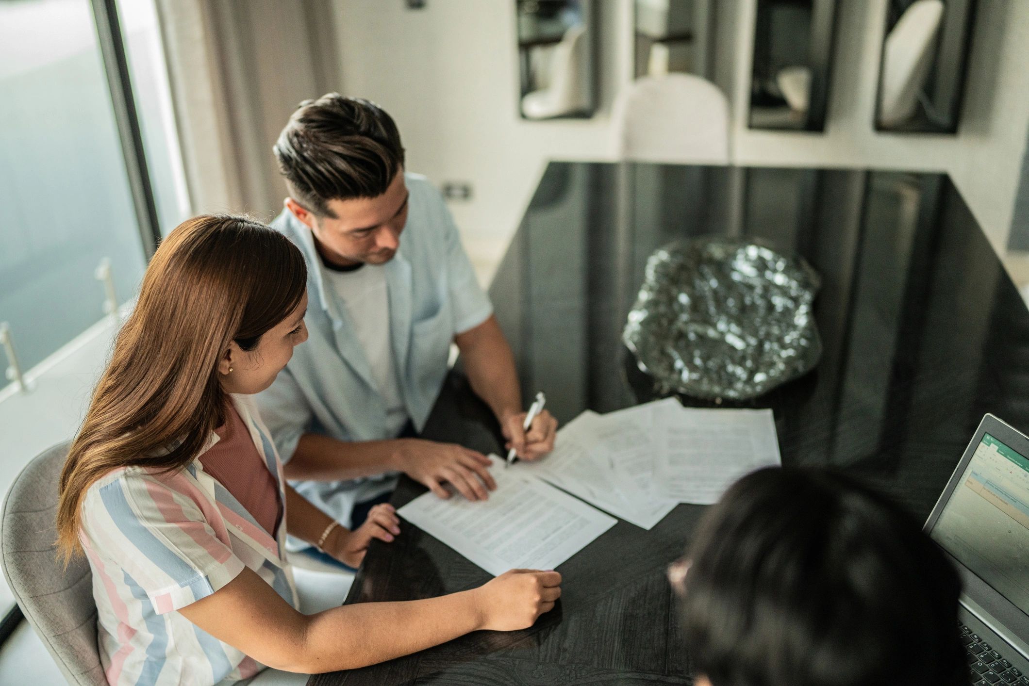 Couple reviewing and signing mortgage paperwork at home